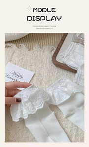 Close-up of white lace ruffle socks with delicate embroidery on warm textured background