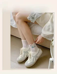 Gros plan de chaussettes en coton blanc avec motif de chat et baskets décontractées