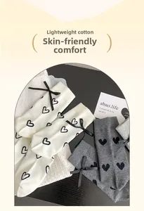 Détail de chaussettes en coton style ballet avec motifs de cœurs noirs et nœuds rubans