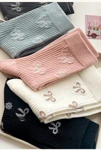 Detail of ribbed knit cotton socks showing delicate bow patterns in multiple pastel colors