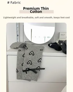 Détail de chaussettes grises en coton avec motifs de cœurs et nœuds en ruban noir