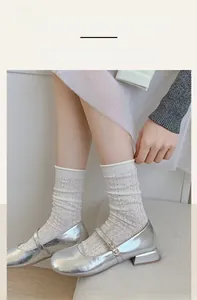 Detailed close-up of white mesh mid-calf socks featuring hollow heart patterns and wavy edges