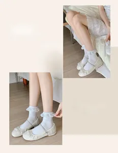 Detail of white cotton socks with wide lace ruffle trim worn with Mary Jane shoes