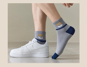Detailed view of gray cotton crew socks with navy heel and yellow smiley face pattern