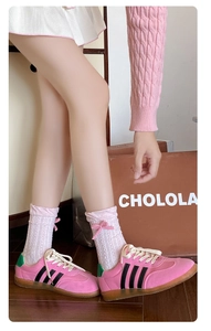 Detail of pink cable knit socks featuring silk bow accents and casual pink sneakers
