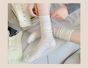 Close-up of white breathable mesh socks with lace patterns and cherry embroidery details