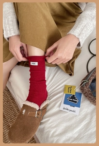 Detail of red ribbed wool socks with egg label paired with brown suede buckle clogs