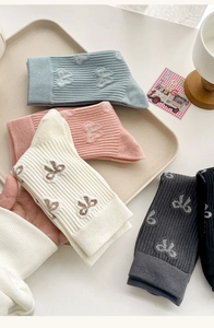 Detail of cotton crew socks featuring vertical knit texture and embroidered bow patterns