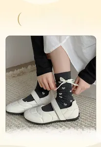 Gros plan de chaussettes grises à cœurs avec nœuds satinés et chaussures Mary Jane