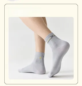 Dettaglio di calzino grigio da uomo con ricamo 'Socks' giallo e strisce decorative