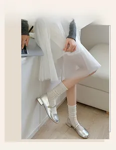 Detail of silver Mary Jane shoes with low square heels paired with white mesh crew socks