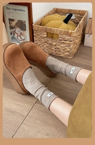 Close-up of brown suede platform mules worn with ribbed knit socks in a warm aesthetic