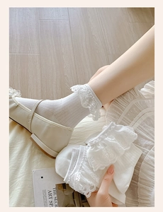 Detail of white cotton blend socks with delicate floral lace ruffles and embroidery