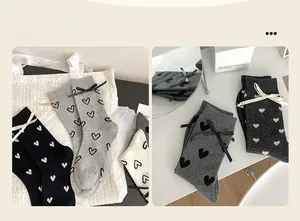 Détail de chaussettes style ballet avec nœuds en ruban et motifs de cœurs gris et blancs