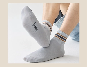Close-up of light grey ankle socks with orange stripes and lammy logo on the sole