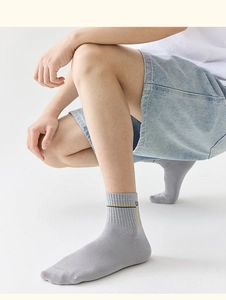 Dettaglio di calze da uomo in cotone grigio chiaro con strisce gialle e motivo a lettere