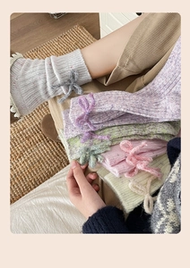 Close-up of cable knit cashmere socks featuring cute bow details in various pastel colors