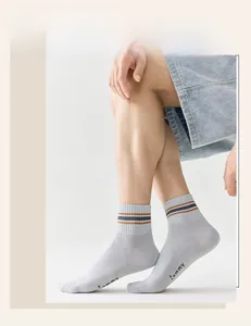 Detail of light gray cotton socks with orange striped cuffs and tammy printed on the sole