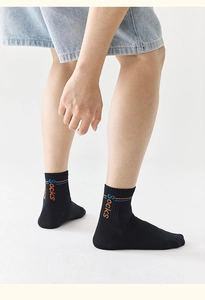 Dettaglio calzino sportivo nero con strisce arancioni blu e testo ricamato sulla caviglia