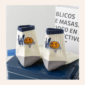Detailed close-up of cream knit ankle sock with blue cuff and cartoon smiley face pattern