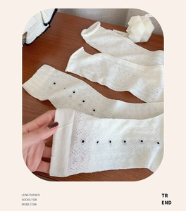 Detailed close-up of white hollow-knit socks with black polka dots and rolled cuffs