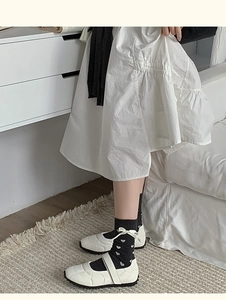 Détail de chaussettes gris foncé à motif cœur avec des chaussures Mary Jane blanches