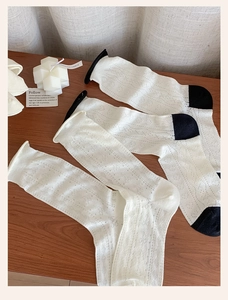 Detailed view of white mesh crew socks with breathable hollow patterns on wooden background