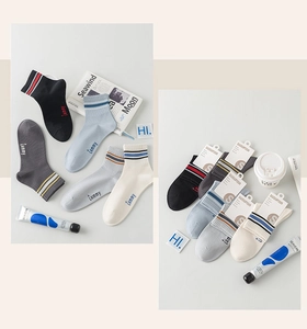 Close-up of five pairs of striped cotton socks with letter embroidery and packaging