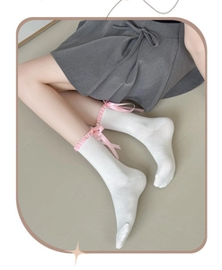 Detail of white mid-calf socks with pink silk bows and delicate pleated ruffles