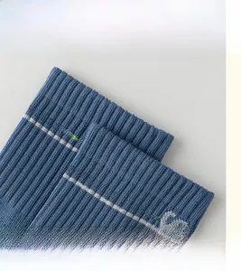 Dettaglio del polsino elastico a coste con strisce verdi e ricamo della lettera CS