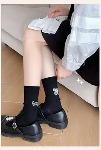 Close-up of black mid-calf socks featuring white letter embroidery and a sweet bow pattern