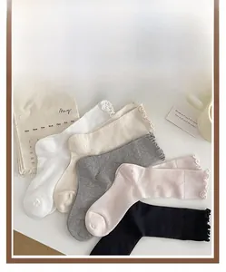 Dettaglio di cinque paia di calzini con volant nei colori bianco, crema, grigio, rosa e nero