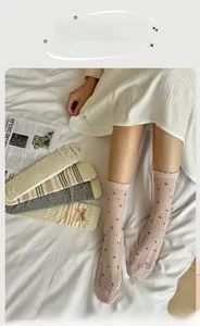 Detail of sweet Lolita crew socks with lace bows and floral knit patterns on white bed