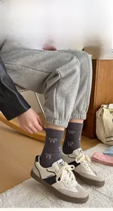 Detail of dark grey crew socks with white bow jacquard pattern and elastic cuffs