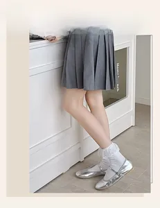 Detail of white lace trim socks paired with silver Mary Jane shoes and pleated skirt
