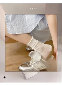 Dettaglio di calze a rete bianche con balze indossate con sneaker argentate