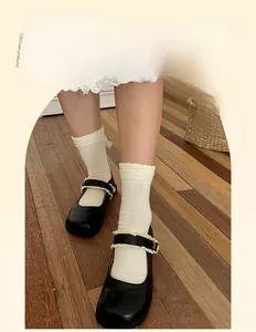 Dettaglio calzini bianchi con bordo in pizzo abbinati a scarpe Mary Jane nere lucide