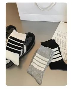 Three pairs of striped mid-calf socks in black, white, and grey with a knit texture