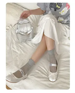 Dettaglio di calze grigie con volant abbinate a scarpe Mary Jane e mini zaino argentato