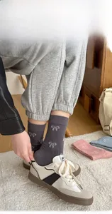 Detail of dark grey crew socks with white bow pattern and reinforced heel fit