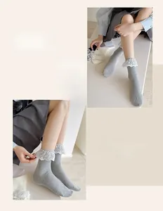 Detail of grey ribbed knit mid-calf socks with delicate white lace trim and dots