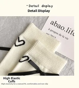Détail de chaussettes en tricot blanc avec broderie cœur noir et nœud en satin
