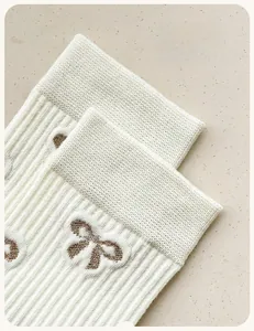 Detailed view of white ribbed knit cotton socks with high-elastic cuff and brown bow detail