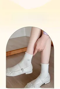 Close-up of white ribbed crew socks with gray butterfly embroidery and Mary Jane shoes