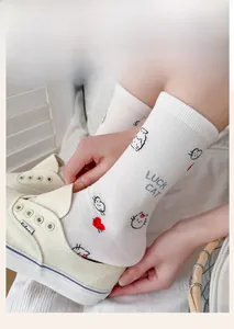 Detail of white cotton crew sock with Lucky Cat graphic and text shown with a shoe