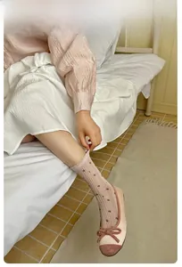 Detail of pink agaric lace socks with delicate floral patterns in a cozy indoor setting