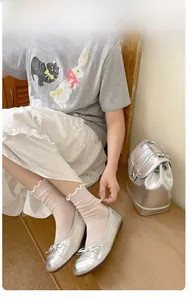 Dettaglio calzini beige con volant a maglia abbinati a ballerine argentate con fiocco