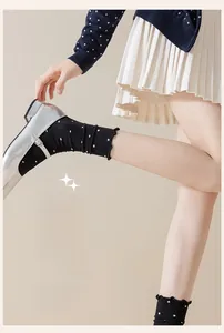 Detailed view of black polka dot socks with ruffle edges paired with silver Mary Jane shoes