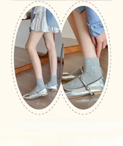 Detail of grey socks with blue butterfly embroidery paired with silver Mary Janes