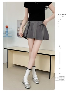 Detail of grey pleated mini skirt with decorative double bows and academic style
